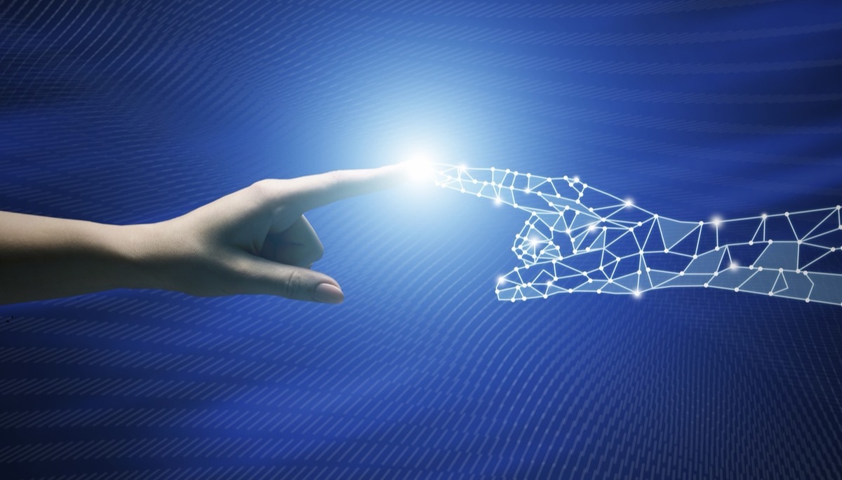 A human hand reaching toward a digital wireframe hand, symbolizing the connection between humans and AI