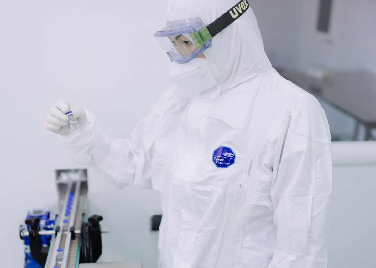 A scientist in protective equipment working on pharmaceutical drug production in a laboratory